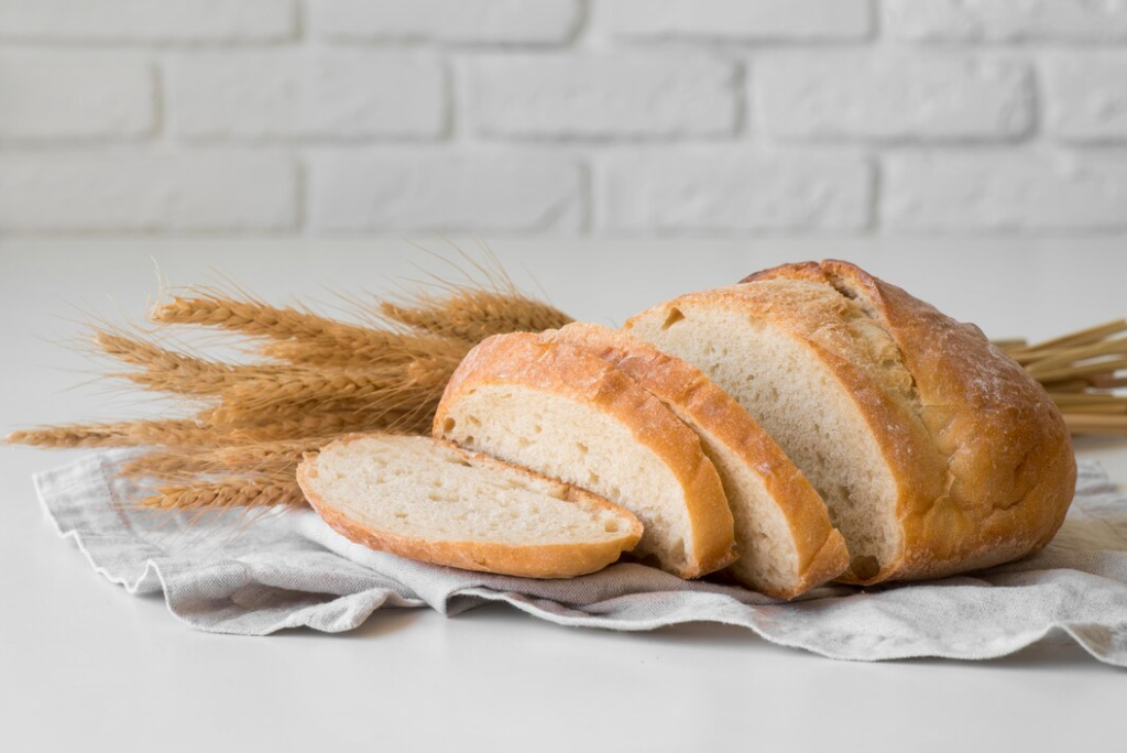 Sourdough sandwich bread loaf with a golden-brown crust sliced on a wooden cutting board.