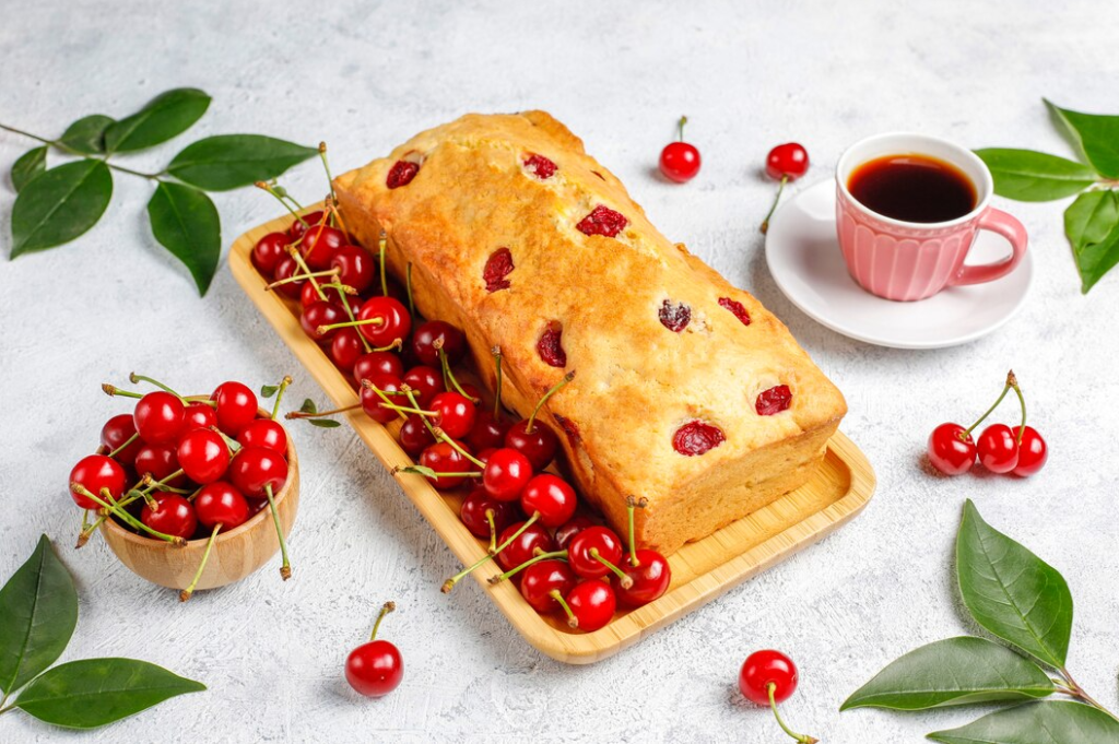 Freshly baked strawberry bread with slices of fresh strawberries on a wooden cutting board.