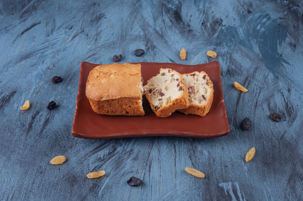 Homemade date nut bread sliced on a wooden board with nuts and dates