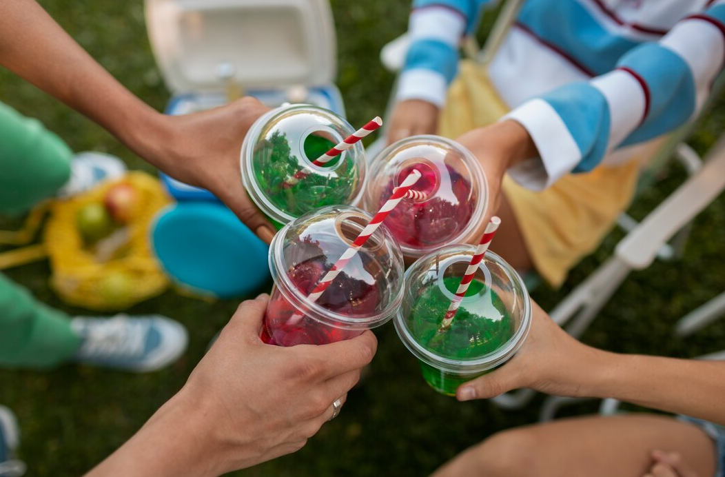 Colorful bug juice camp drink in a glass pitcher with fresh fruit garnish.