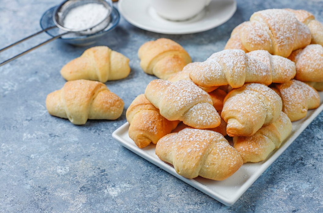 Freshly baked Swiss Gipfeli pastries on a wooden board