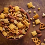 A bowl of Chex Mix coated in savory seasoning with pretzels, cereal, and nuts